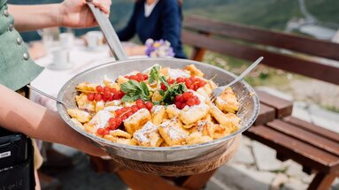 Kaiserschmarrn mit Beeren und Minze wird in einer Pfanne auf einer Almhütte serviert. | © SalzburgerLand Tourismus - Chris Perkles