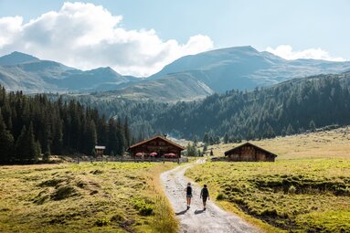 Wanderer auf einem Weg zu Durchgangalm, umgeben von grünen Wiesen und Bergen. | © Ferienregion Nationalpark Hohe Tauern - Mathäus Gartner