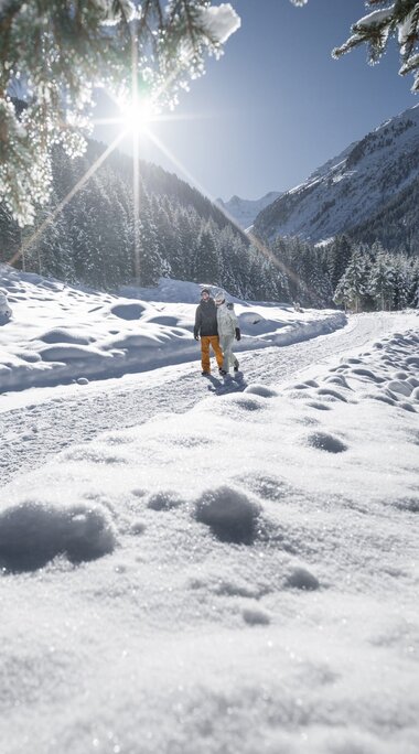 Winter hiker on sunny snow trail through snowy mountain scenery. | © Holiday Region Nationalpark Hohe Tauern - Daniel Breuer