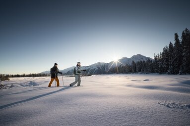 Two snowshoers at sunrise in a snowy valley. | ©  Hohe Tauern National Park holiday region - Daniel Breuer